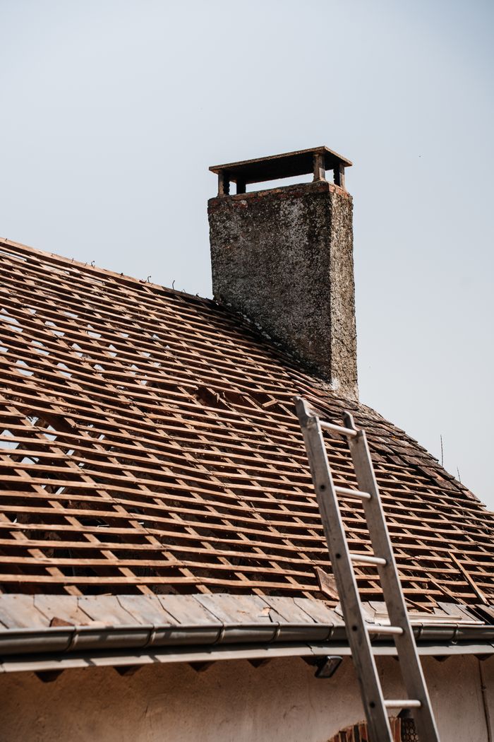 A traditional rooftop under renovation with visible chimney and ladder.